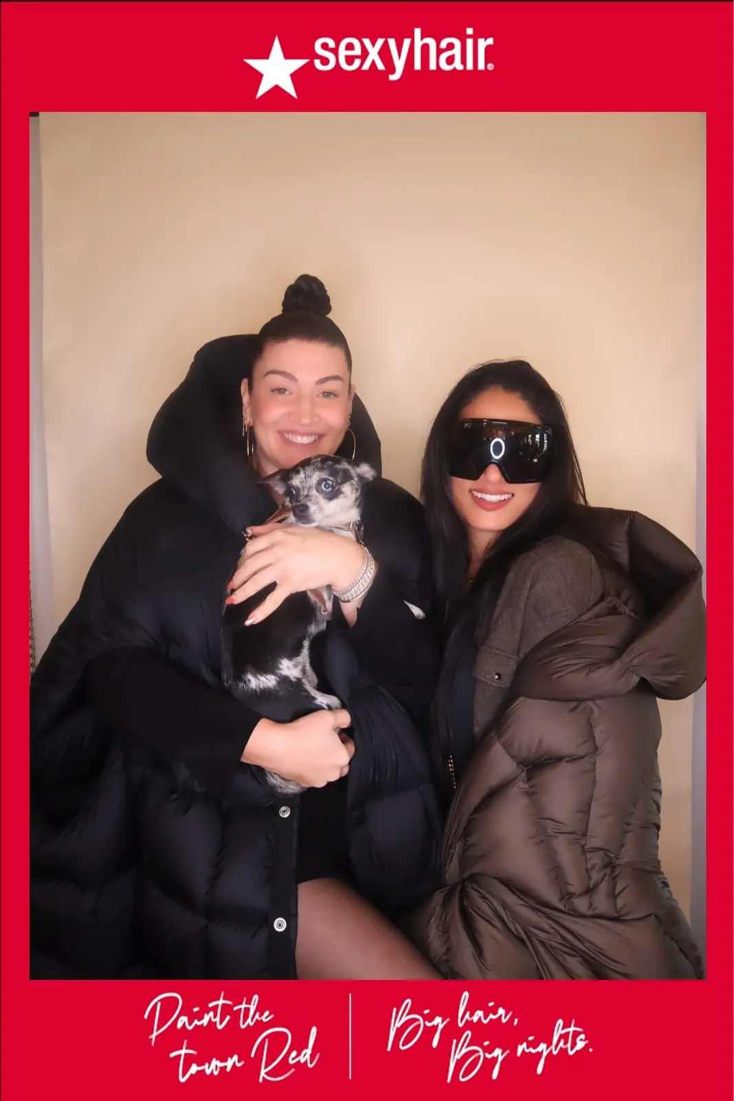 Two guests posing with a small dog at the SexyHair Paint the Town Red booth