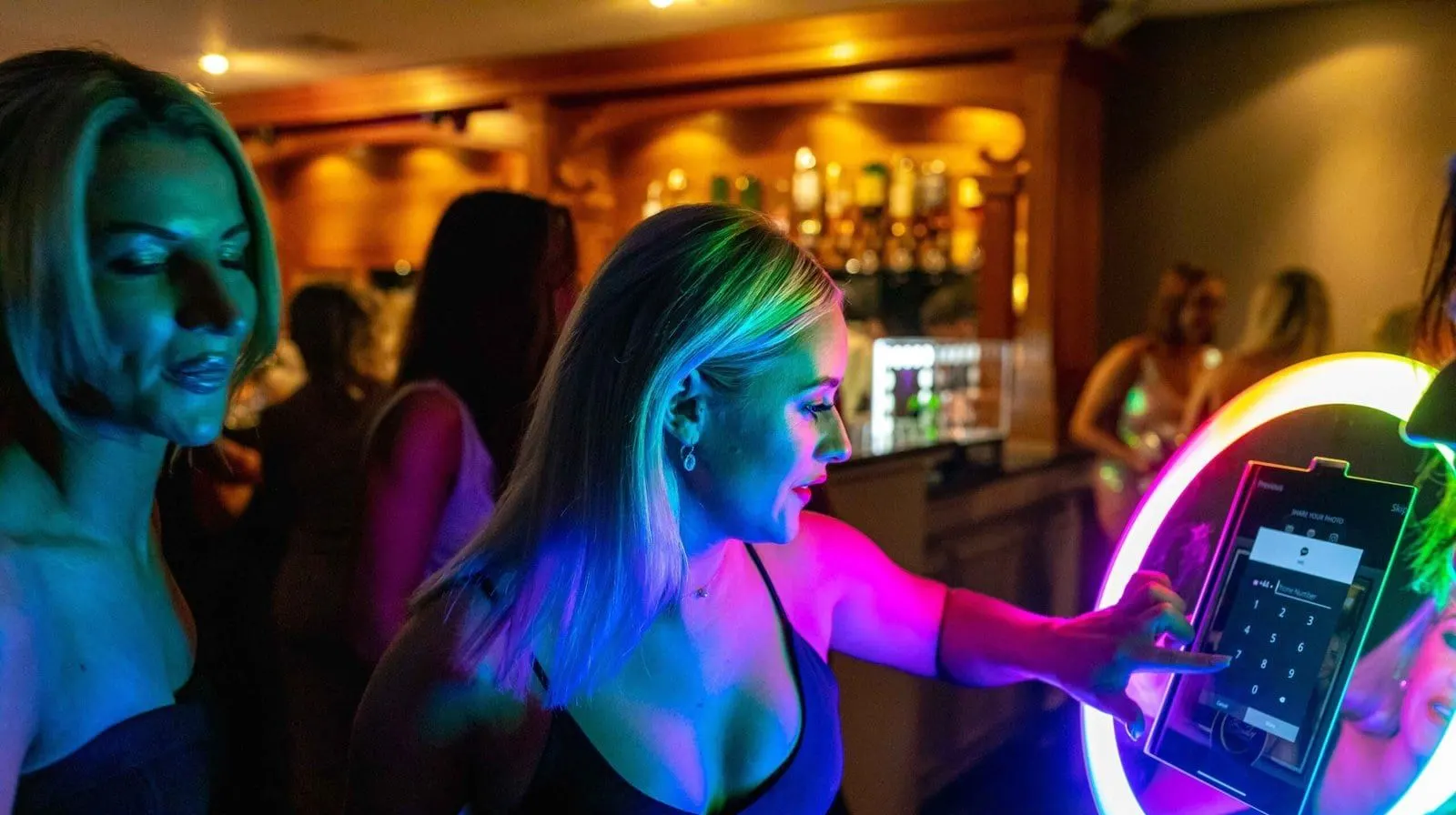 Attendant using a handheld roaming photo booth with guests